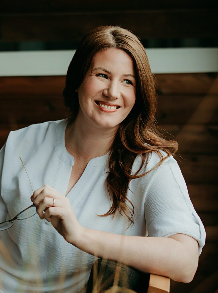 Dr Sarah Adams holding glasses, seated outdoors. She teaches courses in insomnia and ADHD at drsarahadams.com